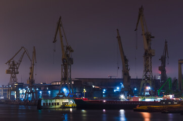 SHIPYARD - Cranes, wharves and industrial buildings in night illumination