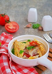 Fish fillet baked with tomatoes and garlic in a lavash bread envelope in a white portioned frying pan on a gray concrete background. Fish recipes.