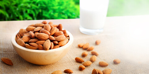 Almonds or nuts in brown bowl with almond milk on background.