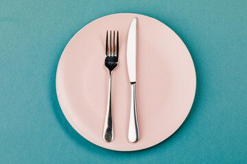 Knife, plate and fork on a green background.