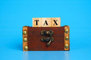 A picture of woodeen block written TAX on the the gold chest on blue background