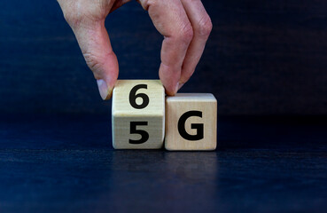 Time to 6G symbol. Male hand turns wooden cube and changes sign 5G to 6G. Technology, business, network, communication and 6G concept. Beautiful dark wooden background, copy space.