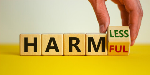 From harmful to harmless. Male hand turns the cube and changes word 'harmful' to 'harmless'....