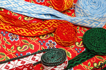 Multicolored ethnic background. Bright wool knits and hobbies. Handmade. Folk crafts. Ethnic folklore serving napkins made of thread on a black background. Twisted threads and knots. Ribbons and belts