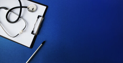 Doctor's workplace. Top view on a blue background with medical equipment - stethoscope, tablet with a blank sheet of paper, glasses. Medical concept.