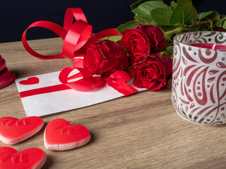 Red roses with candles, red hearts and white card with ribbon