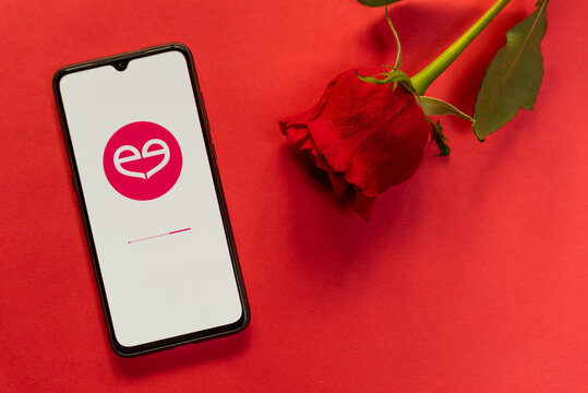 London, UK - 6 january 2021: meetic dating app logo closeup on mobile phone with red rose. Concept of online dating . Romantic flat lay on red background