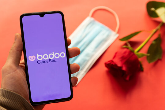 London, UK - 6 january 2021: badoo dating app logo on mobile phone with face mask and red rose. Concept of dating during covid19 pandemic. hand holding mobile phone