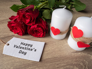 Red roses next to white candles and red hearts and white note