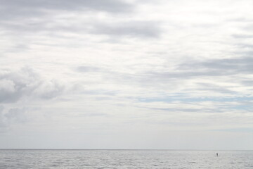 sea scene, lonely person paddle surfing in the ocean far from shore, a minimalist panoramic point of view of a cloudy sky