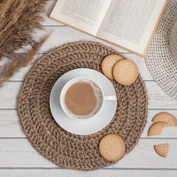 Flatlay with cap of americano or espresso jute mat cookies and book