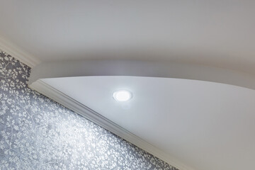 Detail of corner ceiling with intricate crown molding. Suspended ceiling and drywall construction in empty room in apartment or house. Stretch ceiling white and complex shape.