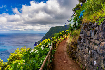 Landscape with trail looking from Miradouro da Ponta do Sossego in direction of Ponta da Madrugada on a sunny day, Sao Miguel. Viewpoint of Ponta do Sossego. Sao Miguel, Azores, Portugal.