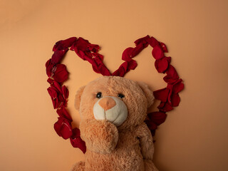 Many red rose petals lie in the shape of a large red heart