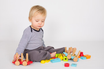 Small baby boy is playing with colourfull wooden block isolated on white background. Creativity concept with copy space.