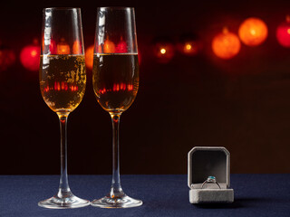Two glasses of champagne and next to them there is a white box with ring