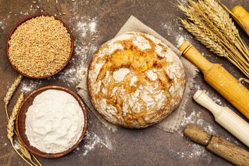 Fresh bread with wheat ears and a bowls of flour and grain