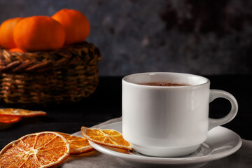 Cup of tea with dried orange slices on black wooden background