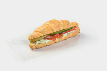 Croissant Sandwich with cucumber and salmon on a light gray background with shadow