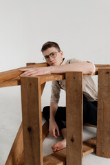 a young guy sits in a wooden box looking sadly at the camera