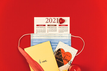 Creative concept for Valentine's Day during COVID-19 pandemic, calendar, red heart, envelop, composition with the mask on red background