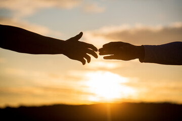 Outstretched hands, salvation, help silhouette, concept help. Giving a helping hand. Rescue, helping gesture or hands. Two hands silhouette on sky background, connection or help concept