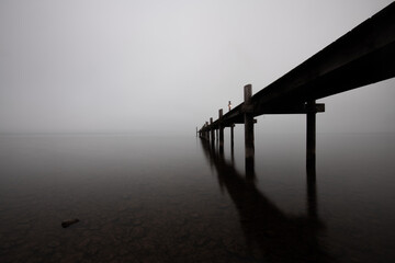 Mole (pier) on the „Chiemsee“ lake in Bavaria, Germany. Wooden bridge in winter time with...