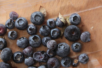 Close up the blueberry (Cyanococcus)  fruits in the plastic container on a wood backgroud. Fresh organic blueberries
