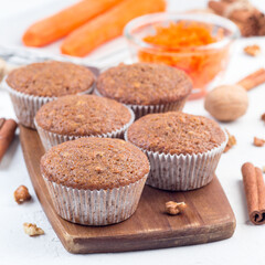Homemade carrot cake muffins with walnuts on a wooden plate, square