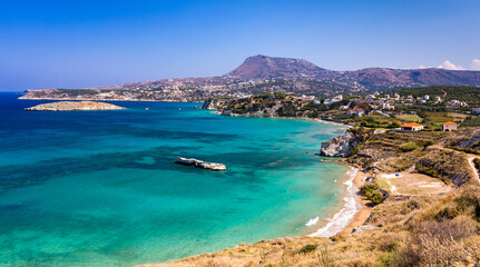 Greek holidays, beautiful Kalyves village with turquoise sea in Crete island, Greece. View of Kalyves beach, Crete. Tourists relaxing on the beach and views to the mountains, Kalyves, Crete, Greece