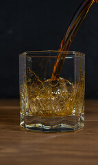 Whiskey drinks on wood with ice cubes and splash