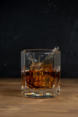 Whiskey drinks on wood with ice cubes and splash