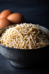 Bowl of traditional Turkish noodle (raw) with eggs on dark background. Turkish style domestic hand made noodle (eriste) on wooden background.