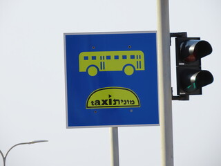 Road sign Public transport lane (buses and taxis) and traffic lights close-up in Haifa in Israel. The word taxi is written in two languages English and Hebrew.