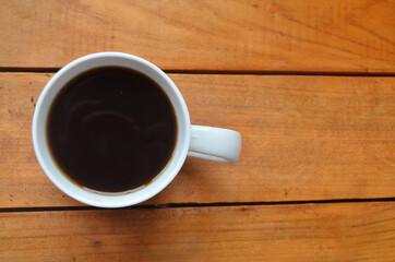 White cup with coffee on a wooden background.