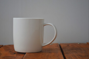 White cup with coffee on a wooden background.