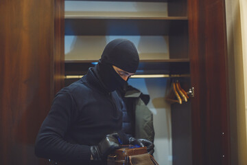 Full length of robber. Man with flashlight and bag in living room. Robber pulls things out of the...