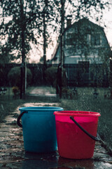 Two plastic buckets - red and blue in the rain - 403692303