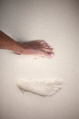 typos of bare feet in the sand and near the foot
