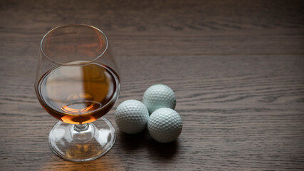 BOURBON CUP WITH GOLF BALLS ON RUSTIC WOODEN TABLE AND SPACE FOR TEXT