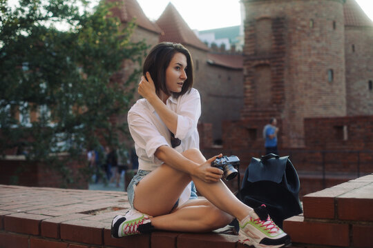 Young hipster girl with a camera in an old European city. The girl is traveling
