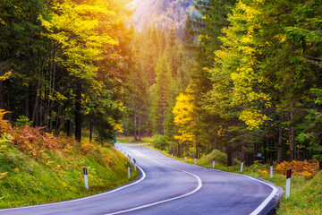 Obraz premium Mountain road. Landscape with rocks, sunny sky with clouds and beautiful asphalt road in the evening in summer. Vintage toning. Travel background. Highway in mountains.