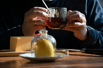 Breakfast. Cheese on a cutting board out of focus. A man with a mug of tea  in the background in focus.