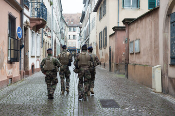 Portrait on back view of military mens patroling in the street whit shotguns