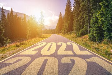 Empty asphalt road and New year 2022 concept. Driving on an empty road in the mountains to upcoming 2022 and leaving behind old 2021. Concept for success and passing time.