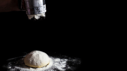 the chef sprinkles flour on the dough. making pizza dough. sifting flour.