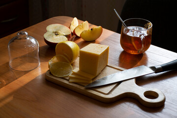 Table in the kitchen with breakfast. Tea, cheese, lemon, apple.