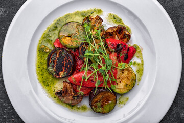 Chopped baked grilled vegetables with mushrooms, zucchini, eggplants, bell peppers, mushrooms, on a white plate with sauce