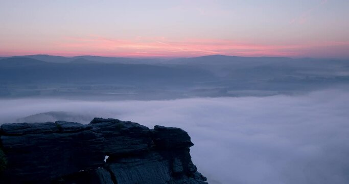 Beautiful time lapse video of the Saxon Switzerland landscape. View from Lilienstein into the valley during dawn sunrise with a lot of fog or mist in the morning.