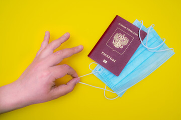 the hand pulls out a medical mask from the passport. The concept of travel between countries during the coronavirus outbreak